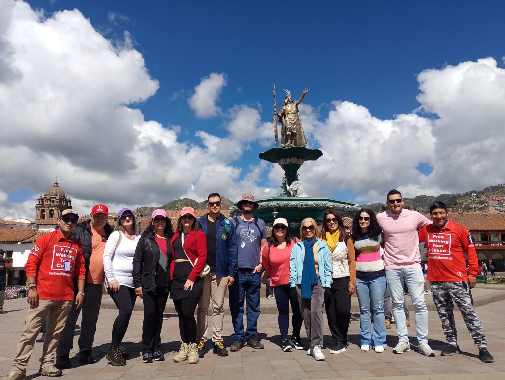 Tour guides of Free Walking Tour Cusco standing in front of the Inca statue, welcoming guests at the official meeting point in the city center.