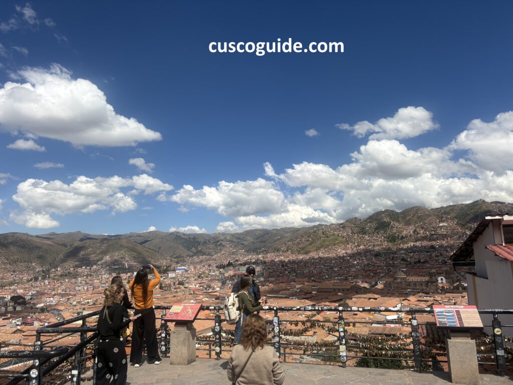 Panoramic view of Cusco City from the San Blas Viewpoint, featuring red-tiled roofs and surrounding Andean mountains.